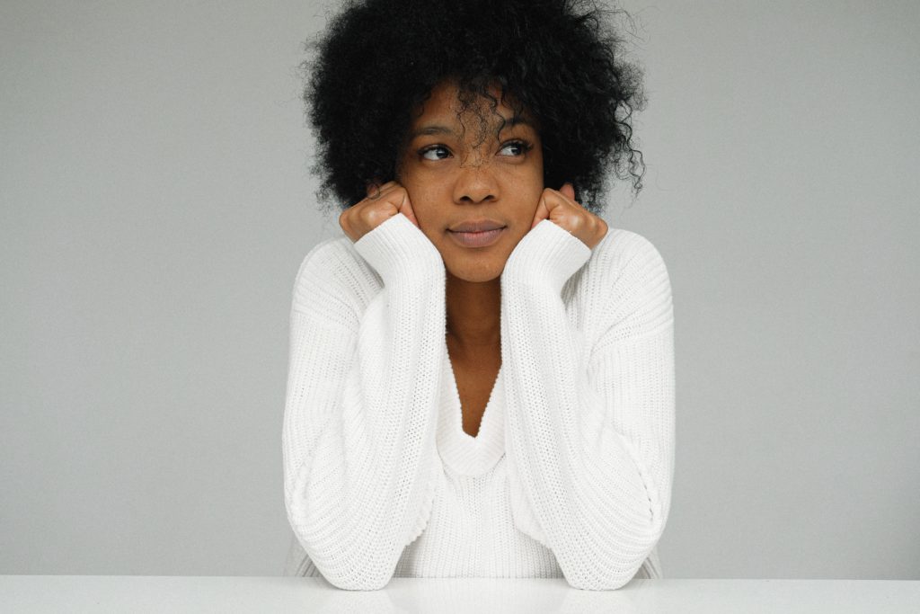 woman in white sweater holding chin